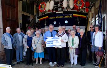 Barbar Needham Nranch President Vale of York branch presenting their cheque to John Porter Lifeboat Visitor Officer. Colin Woodhead Chairman of Scarborough Lifeboat Management Group is 3rd from right on the back row.